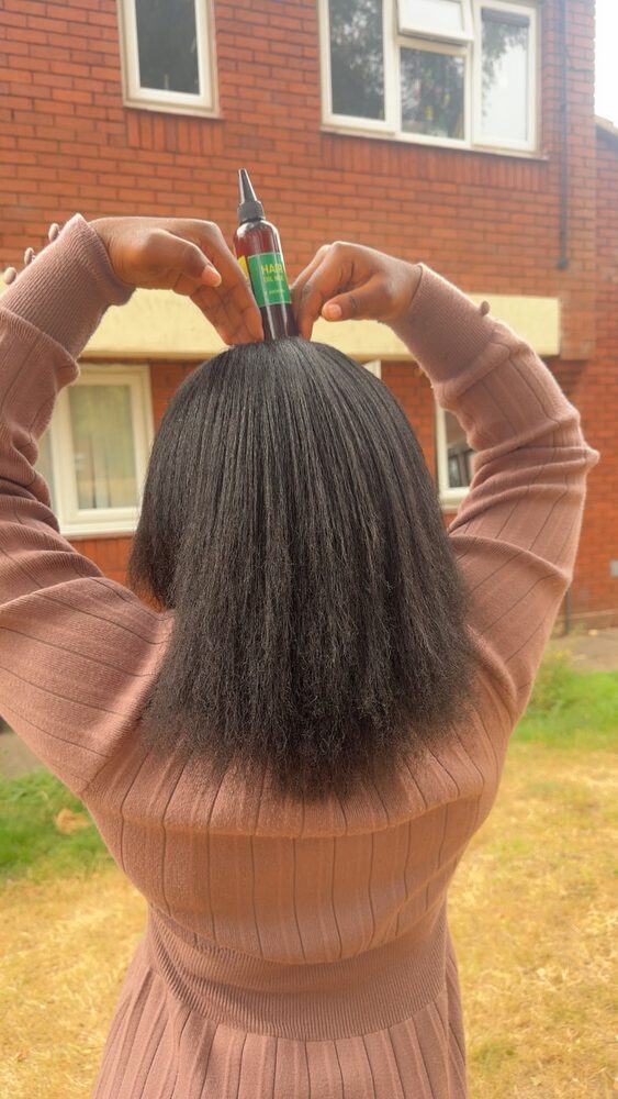 Long natural hair, seen from behind, with a bottle of Hair Oil Mix