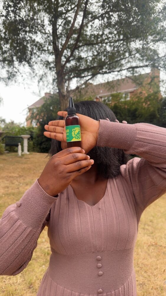 Holding a bottle of Hair Oil Mix outdoors